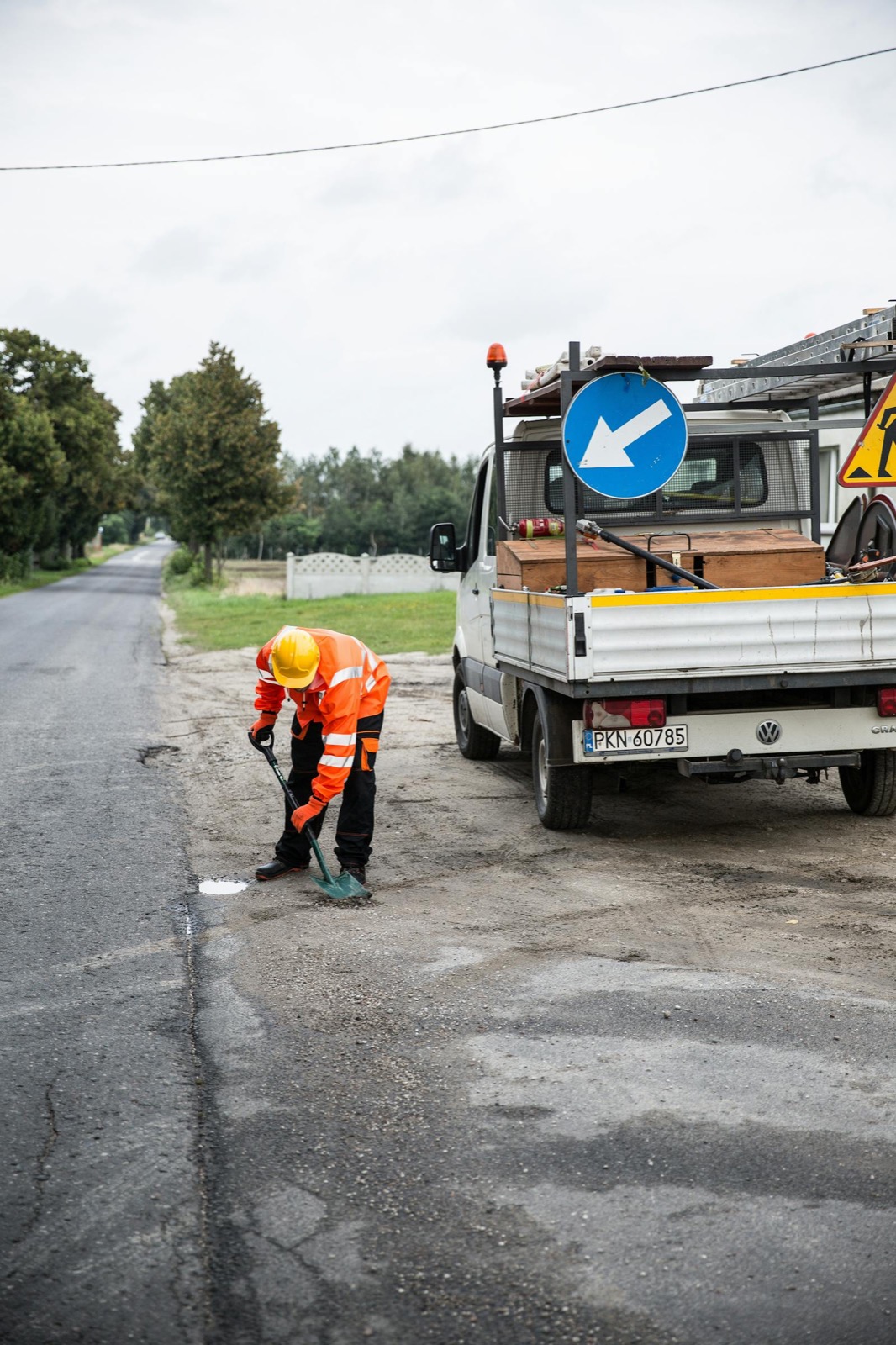 A road-maintenance worker fixing a pothole beside a service truck